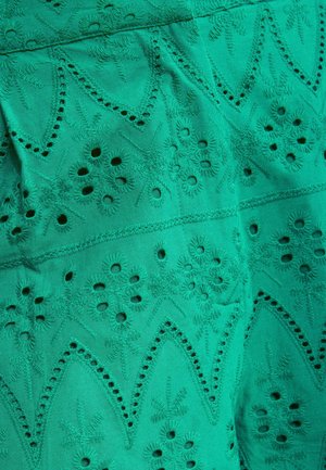 Petrolfarbener Stoff mit aufwendiger Blumenstickerei und Ösenmustern, die in symmetrischen, sich wiederholenden geometrischen Formen angeordnet sind.