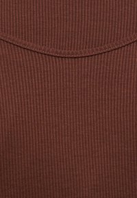 Κοντινή όψη καφέ ριπτό πλεκτού υφάσματος με λεπτομέρεια κυρτής ραφής.