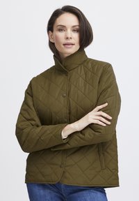 Olive roheline tikandiga jakk kõrge kaelusega, nööpidest lukuga ja küljetaskutega. Omab teemantmustrit ja lõdvestatud lõiget.