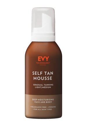 Zelfbruinende mousse in een bruine fles met een witte pompdeksel. Heeft oranje tekst voor branding en productdetails. Geurvrij, geschikt voor alle huidtypes.