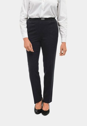 Marineblauwe op maat gemaakte broek met een gladde textuur, elastische tailleband en een zilveren hardwaredetail. Gekleed met een witte blouse en zwarte hakken.