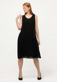 Vestido negro sin mangas con bordado de cuentas florales, de longitud a la rodilla, tela suave, escote redondo y una silueta fluida.