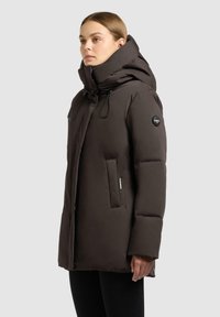 Parka imbottita marrone con colletto alto, cappuccio regolabile con cordino, tasche laterali e patch con logo sulla manica. Texture liscia con design elegante.