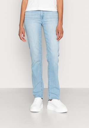 Világoskék farmernadrág egyenes szárú szabással, klasszikus öt zsebes kialakítással és enyhe kopással. Fehér sportcipővel párosítva.