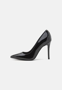 Zwarte gepatenteerde leren hoge hakken met een puntige neus en een gladde textuur, met een slanke stilettobruik. Geen zichtbare versieringen.