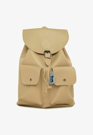 Beżowy skórzany plecak z zaokrąglonym klapą, srebrnymi detalami i dwoma przednimi kieszeniami. Posiada zapięcie na sznurek i metkę z logo.