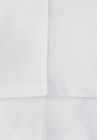 Tela de algodón blanca con textura acanalada, con un corte recto y costuras a lo largo de los bordes. Superficie lisa, sin patrones ni acentos.