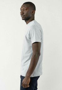 Grijze korte mouwen t-shirt van een katoenmengsel, met een ronde hals en een relaxte pasvorm, gecombineerd met donkere broeken. Simpel, casual ontwerp.