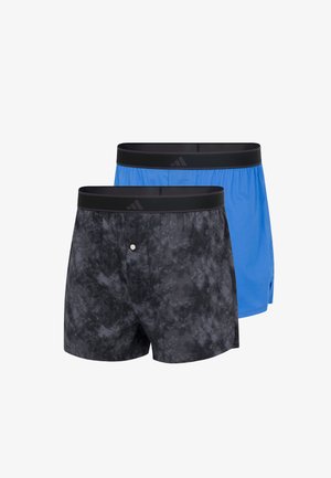 Zwei Herrenslips mit schwarzen Bündchen; ein Paar ist blau, das andere schwarz mit grauem Batikmuster und einem Knopf vorne.