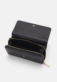 Czarny skórzany portfel z zamkiem błyskawicznym, złotymi akcentami i dwiema przegrodami. Posiada zatrzask i minimalistyczny design.
