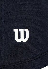 Tejido atlético azul marino con un destacado logo blanco de Wilson; textura suave con detalles de costura. El diseño es simple y funcional.