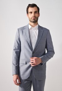 Helle graue Anzugjacke mit blauem Streifenmuster, strukturiertem Design, Reverskragen, Ein-Knopf-Verschluss und weißem Hemd darunter.
