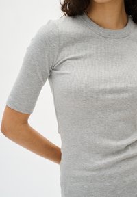 Top scurt cu mânecă raglan gri, cu guler rotund. Textura materialului este moale și ajustată, punând în evidență forma corpului fără embellishments suplimentare.