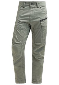 Olivgröna cargobyxor med avsmalnande passform, tillverkade av lättviktigt material, med flera fickor och en dragkedjeficka på sidan.