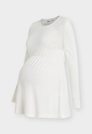 Bela dolgo rokavna nosečniška majica z okroglim izrezom, teksturiranim vzorcem pik in zbranimi detajli pod prsmi za udobje in prileganje.