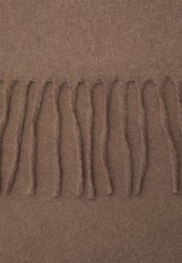 Pruun villane sall pehme tekstuuriga, millel on kergelt frangeeritud servad ja peen herringbone muster. Pind on sile ja ühtlane.
