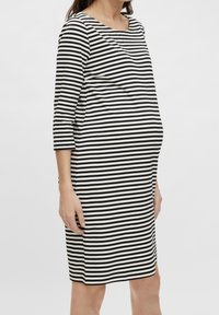 Mustat ja valkoiset raidalliset mekko, polvipituinen, pitkät hihat, pyöreä kaula-aukko, valmistettu pehmeästä kankaasta, vartalonmyötäinen vyötäröltä.