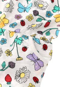Bílá tkanina s barevným květinovým vzorem obsahující sedmikrásky, motýly, berušky a jahody. Obsahuje elastický pas a kapsu.