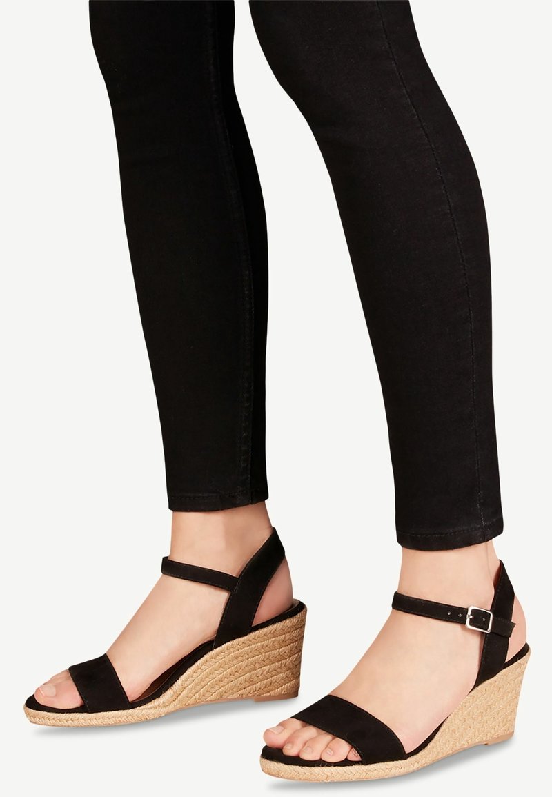 Sandales noires à talon en jute tressé, avec des brides en daim et une boucle à la cheville. Design à bout ouvert qui met en valeur le pied.