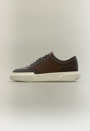 Baskets basses en cuir marron avec des accents marron foncé, des lacets et une semelle épaisse écrue avec le logo "CK" sur le côté.