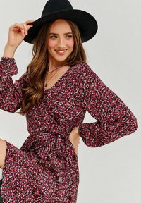 Čierny klobúk, dlhé šaty s kvetinovým vzorom v ružovej a bielej na čiernom pozadí, so zaväzovan�ím v páse a výstrihom do V.