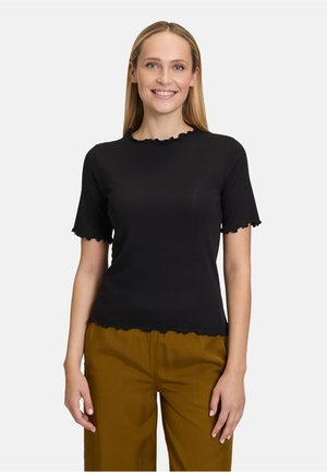 Black ribbed short-sleeve top with a scalloped neckline and hem. Paired with olive green trousers. Smooth texture with a fitted design.
