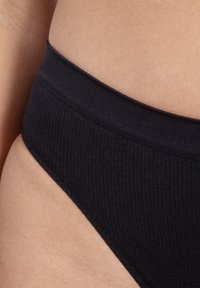 Sous-vêtements noirs côtelés avec une taille haute. Le tissu semble doux, avec une ceinture lisse et une coupe ajustée le long de la jambe.