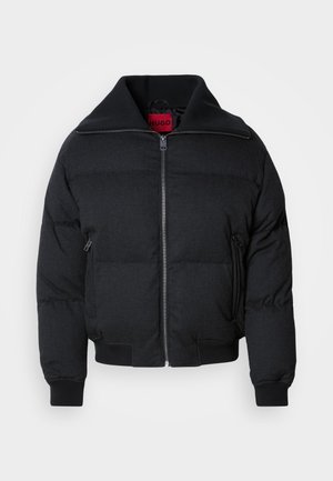 Black puffer jacket featuring a high collar, zip front, two side pockets, and ribbed cuffs. Smooth texture with quilted pattern throughout.