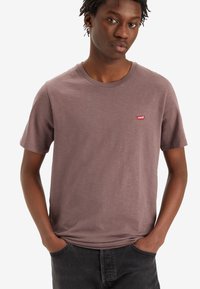 Kurzarm-T-Shirt mit Rundhalsausschnitt in gedämpftem Mauve, aus weichem Stoff; verfügt über ein kleines rotes Levi's-Logo auf der linken Brust.