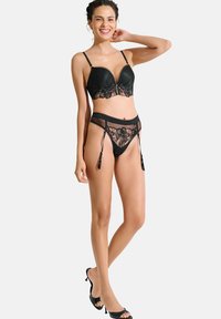 Ensemble de lingerie en dentelle noire comprenant un soutien-gorge rembourré avec un motif floral et une culotte taille haute transparente. Comprend des jarretelles décoratives.