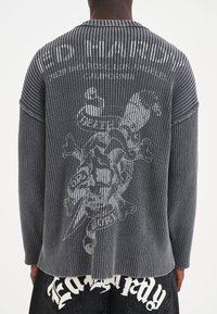 Maglione grigio a maniche lunghe con coste, caratterizzato da una grande grafica sul retro e scollatura rotonda, con una vestibilità rilassata e una leggera texture.