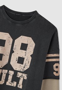 Maglietta a manica lunga stratificata grigio scuro con grande stampa sbiadita "98" e "MULT" sul davanti e "9" con strisce sulla manica.
