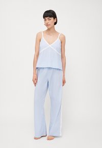Light blue pajama set featuring a cami top with lace trim and wide-leg pants with lace accents along the sides. Soft fabric with a simple design.