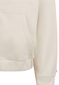 Gros plan sur la manche crème du sweat-shirt et la poche avant avec coutures apparentes et ourlet et poignets côtelés.