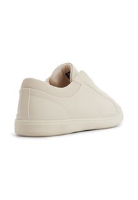 Kremowe slip-on sneakersy z teksturowaną cholewką, okrągłym noskiem i gumową podeszwą z delikatnymi poziomymi żłobieniami.