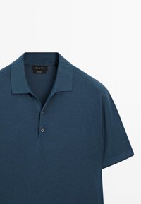 Mørkeblå polo-shirt lavet af bomuld, med en blød tekstur, korte ærmer, klassisk krave og placket med to knapper.