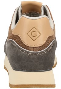Baskets marron et grises avec un dos texturé, dotées d'une languette en cuir beige au talon et d'un logo en forme de diamant. Semelle en caoutchouc avec un crantage.