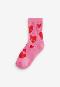 Rosa Baumwollsocken mit einem gerippten Design, geschmückt mit roten Herzmustern, von denen einige ein lächelndes Gesicht haben, auf einem weichen, strukturierten Hintergrund.