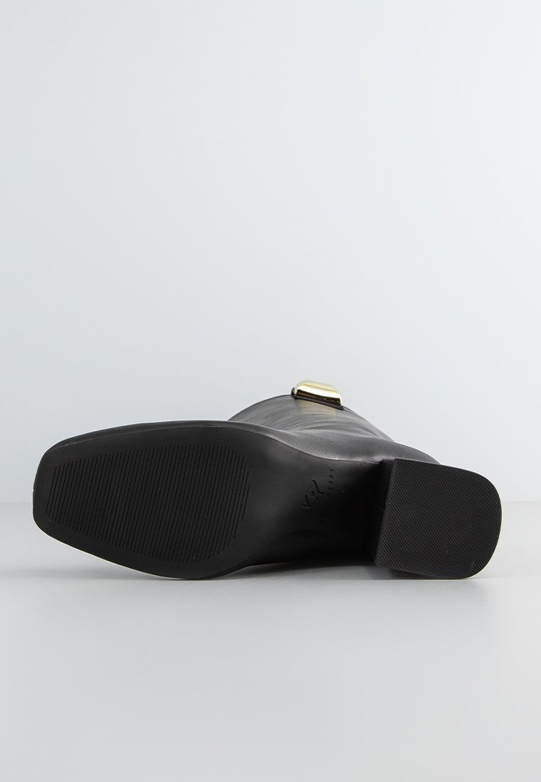 Schwarze Schuhe aus glattem Lederoberteil, mit flacher Gummisohle und einem subtilen strukturierten Muster. Mit einem goldfarbenen Schnallenakzent.