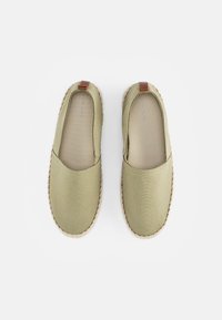 Gröna kanvas slip-on skor med en vävd sula och brunt läderackcent vid hälen. Slät textur, rund tådesign.