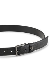 Schwarzer strukturierten Leder Gürtel mit silberner rechteckiger Schnalle und einem kleinen dekorativen metallenen Kreuz an der Gürtelschlaufe, isoliert auf weißem Hintergrund.