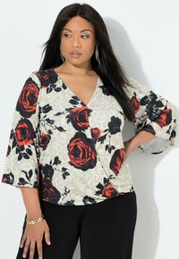 Květinová blůza s výstřihem do V, výraznými červenými a černými růžemi na béžovém pozadí a středními zvonovými rukávy. Hladká textilie.