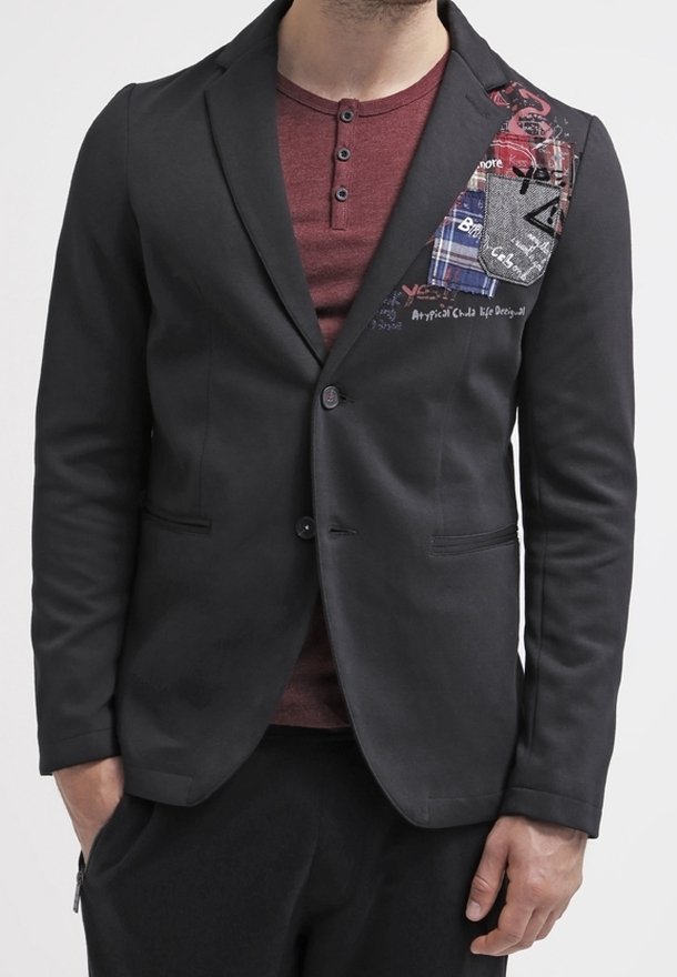 Blazer nero con design aderente, caratterizzato da un accento di patchwork in tessuto scozzese e grafiche sulla zona del petto sinistro. Tessuto strutturato, chiusura con un bottone.
