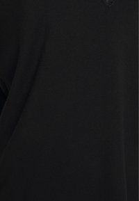 Närbild av svart stickat tyg som visar fin, enhetlig textur och subtil drapering.
