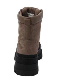 Bruine suède enkellaars met een zwarte rubberen zool, een afgeronde neus, een omslagmanchet en een gestructureerd oppervlak. Voorzien van een achterste trekstrook.