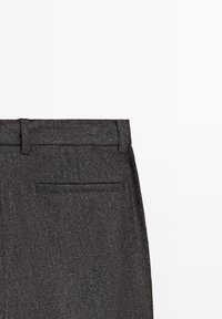 Zbliżenie na ciemnoszare spodnie z tweedu, ukazujące pas w talii, szlufki na pasek oraz pojedynczą tylną kieszeń z listwą na białym tle.