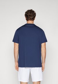 Marineblaues kurzärmliges Shirt mit rundem Ausschnitt und glattem Stoff. Verfügt über Nahtdetails an den Schultern und einen lockeren Schnitt.
