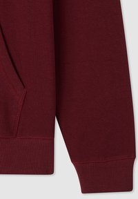 Tessuto di felpa bordeaux con una superficie liscia, dotato di una tasca laterale e polsini a costine. Design semplice senza motivi o accenti aggiuntivi.