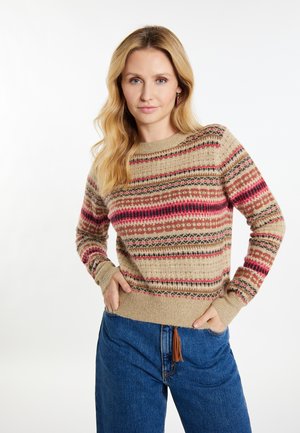 Gebreide trui in beige met meerkleurige strepen in rood, zwart en roomkleur. Het heeft ribgebreide manchetten en een zoom, in combinatie met blauwe denim broek.