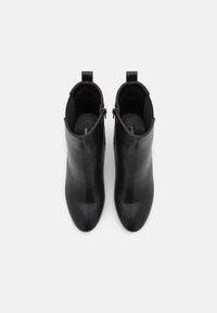 Schwarze Lederknöchelstiefel mit einer schlanken, spitzen Spitze und minimalistischem Design. Sie verfügen über einen seitlichen Reißverschluss und ein strukturiertes Innenfutter.